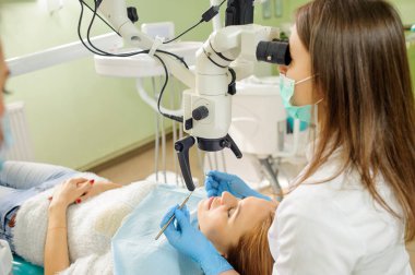 Çürük diş hekimi ofiste mikroskop kullanarak tedavi kadın diş hekimi