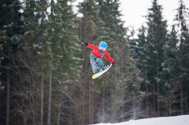Çocuk atlama ve tutar bir taraftan snowboard