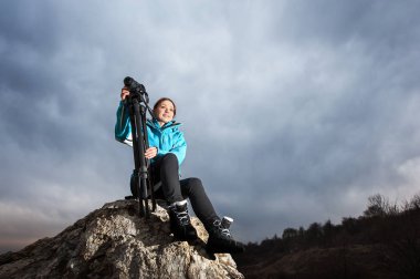 Kadın fotoğrafçı ile fotoğraf makinesi tripod üzerinde büyük kayanın üzerinde