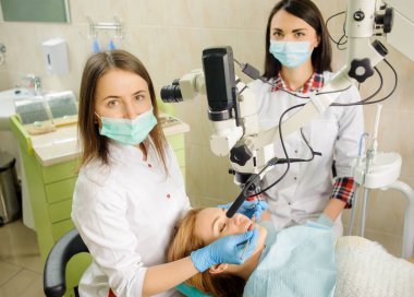 Çürük diş hekimi ofiste mikroskop kullanarak tedavi kadın diş hekimi