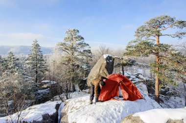 Erkek dağcı neredeyse çadırını kaya üstünde