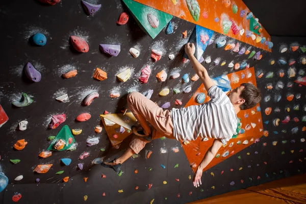 Forte alpinista macho na parede de escalada de pedregulho interior — Fotografia de Stock