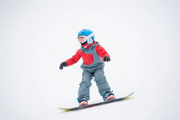 Snowboarder menino cavalgando sobre a encosta — Fotografia de Stock