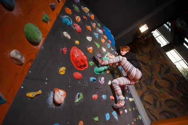 Strong female climber on boulder climbing wall indoor — Stock Photo, Image