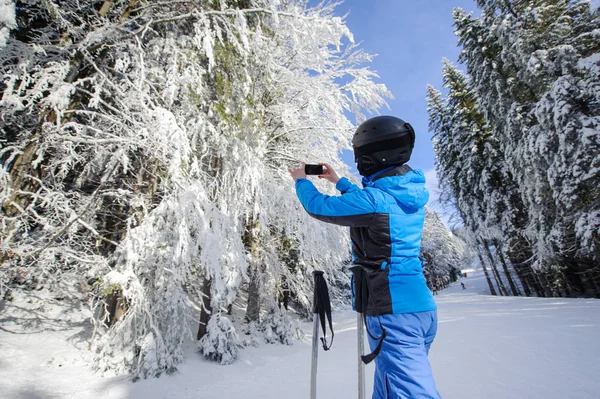 Visão traseira do esquiador tirando foto com seu telefone celular — Fotografia de Stock
