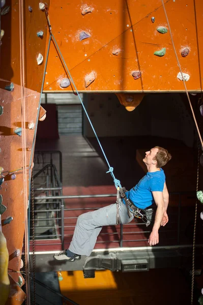 Hombre escalador practicando escalada en pared de roca en interiores —  Fotos de Stock