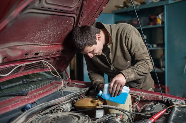 Mechaniker Mann Arbeiter gießt Frostschutzmittel in das Kühlsystem — Stockfoto