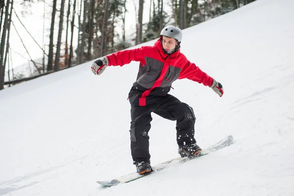 Mannelijke snowboarder rijden naar beneden van de berg in de winterdag — Stockfoto