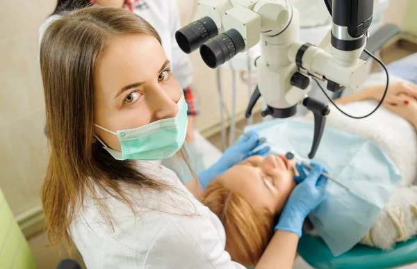 Une dentiste qui traite des caries au microscope au cabinet du dentiste — Photo