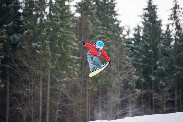 Rapaz saltando e mantém uma mão no snowboard — Fotografia de Stock