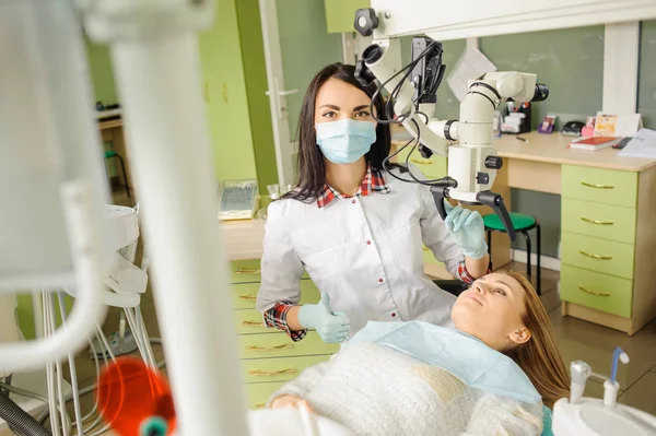 Une dentiste qui traite des caries au microscope au cabinet du dentiste — Photo