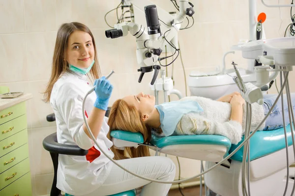 Γυναίκα οδοντίατρος, θεραπεία τερηδόνας, χρησιμοποιώντας μικροσκόπιο στο οδοντιατρείο — Φωτογραφία Αρχείου