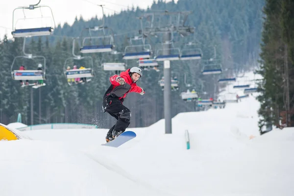 Homem no snowboard pulando sobre a encosta — Fotografia de Stock