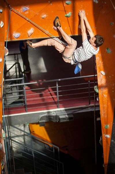 Masculino alpinista praticando escalada na parede de rocha dentro de casa — Fotografia de Stock