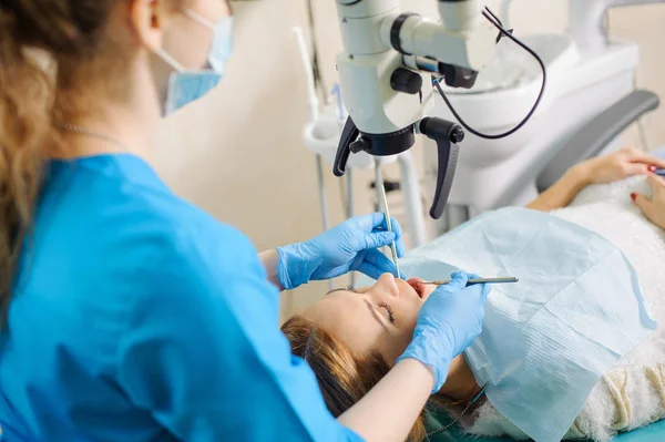 여성 치과 카 리에 스 치과 의사 사무실에서 현미경을 사용 하 여 치료 — 스톡 사진