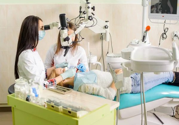 Une dentiste qui traite des caries au microscope au cabinet du dentiste — Photo