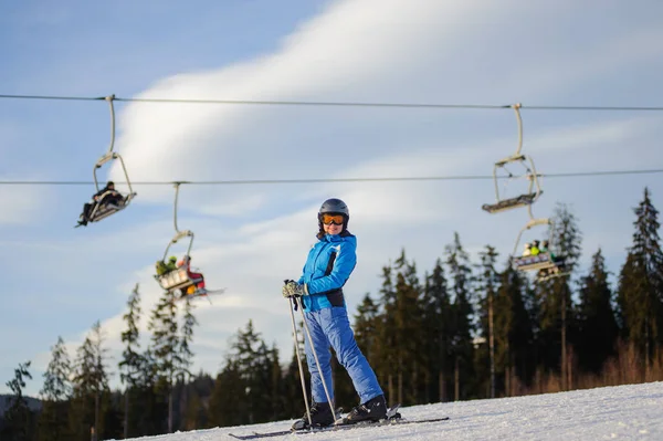 Kvinnliga skidåkare mot skidliften och skog på en solig dag — Stockfoto