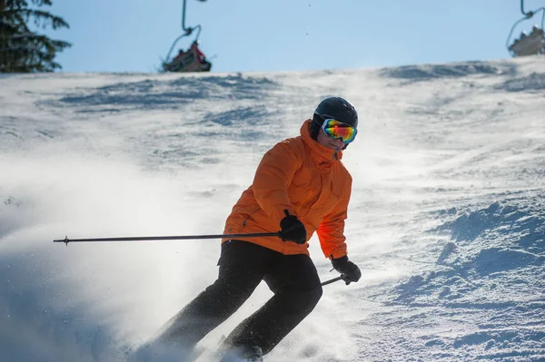 Manliga skidåkare skidåkning nedför vid skidorten mot skidlift — Stockfoto