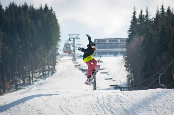 Conduttore femminile sullo snowboard che salta sul pendio — Foto Stock
