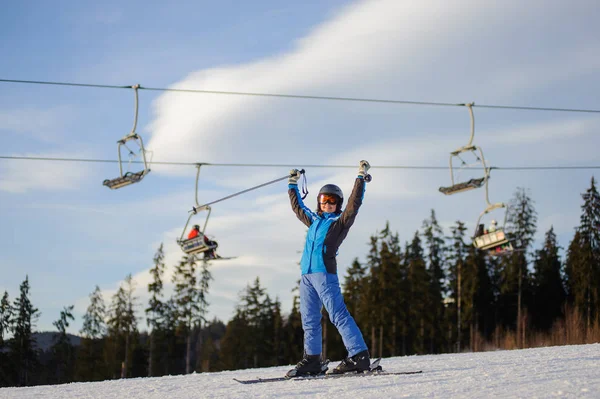 Kvinnliga skidåkare mot skidliften och skog på en solig dag — Stockfoto