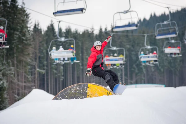 Homem no snowboard pulando sobre um obstáculo — Fotografia de Stock