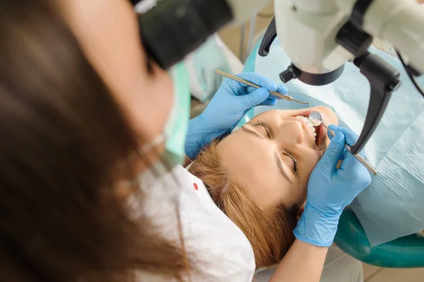 Une dentiste qui traite des caries au microscope au cabinet du dentiste — Photo