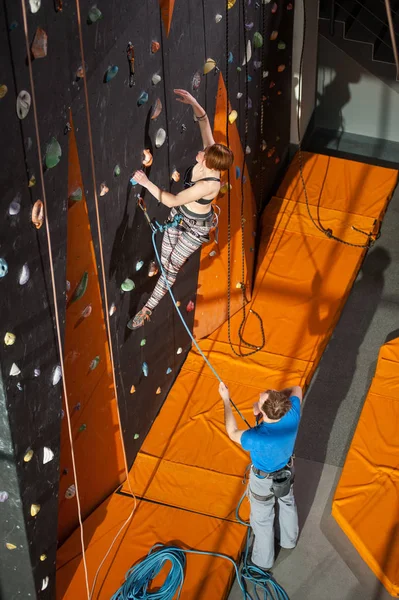 Альпинистка взбирается на крытую скалолазание стену — стоковое фото