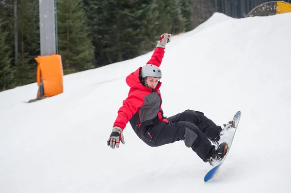 Snowboarder in the moment of falling on the snowy slope