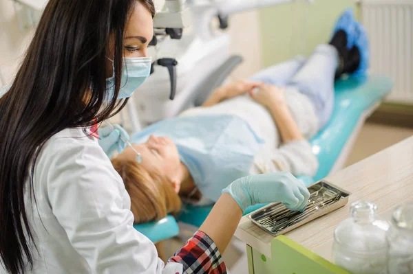 Une dentiste qui traite des caries au microscope au cabinet du dentiste — Photo