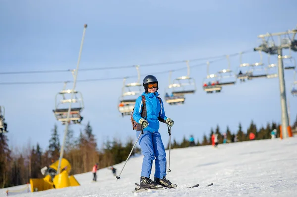 Mujer esquiadora esquiando cuesta abajo en la estación de esquí contra telesilla —  Fotos de Stock
