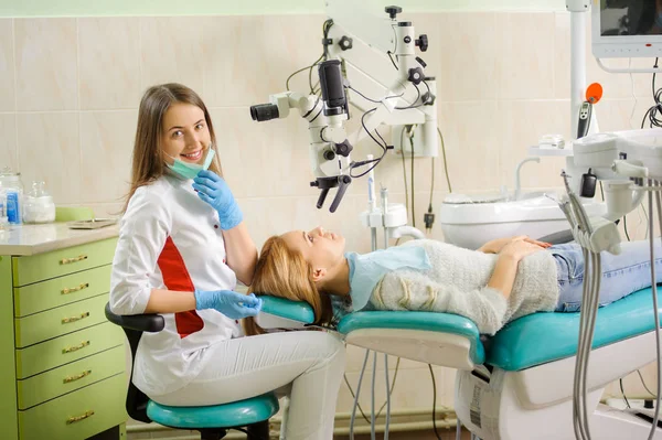 Женщина-дантист лечит кариес с помощью микроскопа в стоматологическом кабинете — стоковое фото