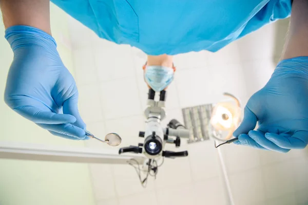 Doutor com um microscópio em uma clínica odontológica — Fotografia de Stock