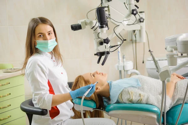 Une dentiste qui traite des caries au microscope au cabinet du dentiste — Photo