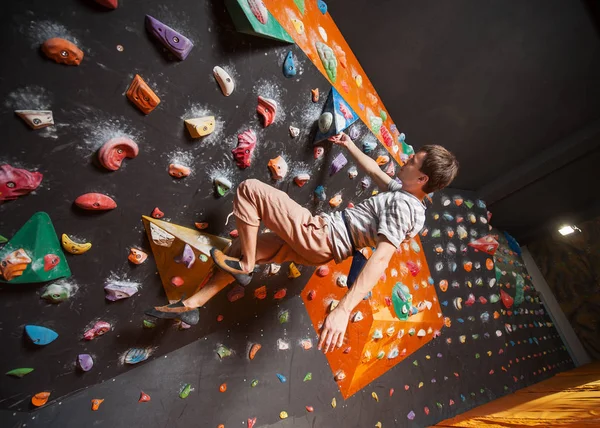 Escalador masculino fuerte en la pared de escalada de roca interior — Foto de Stock