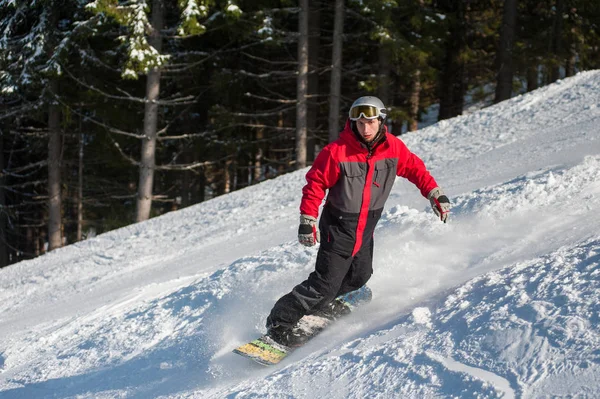 Homem snowboarder desliza para baixo da montanha — Fotografia de Stock