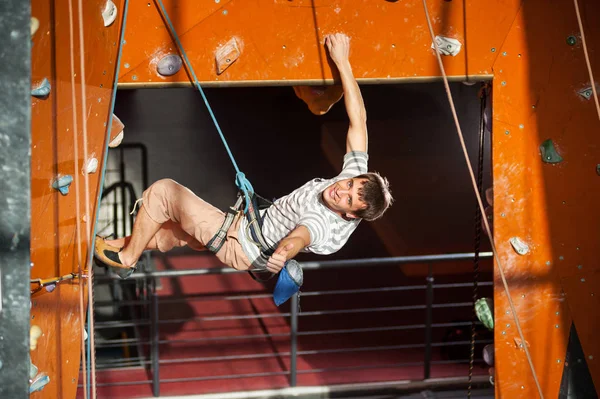 Masculino alpinista praticando escalada na parede de rocha dentro de casa — Fotografia de Stock