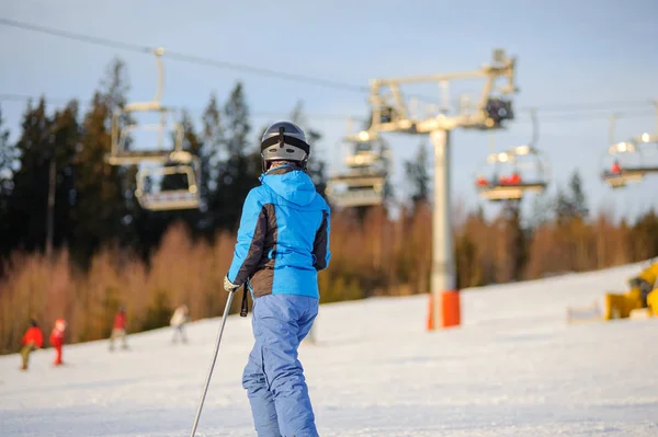 Mulher esquiadora contra ski-lift e floresta em um dia ensolarado — Fotografia de Stock