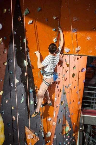 Masculino alpinista praticando escalada na parede de rocha dentro de casa — Fotografia de Stock