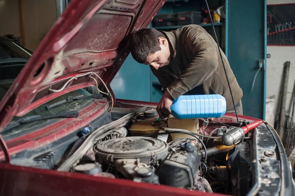 Mechaniker Mann Arbeiter gießt Frostschutzmittel in das Kühlsystem — Stockfoto