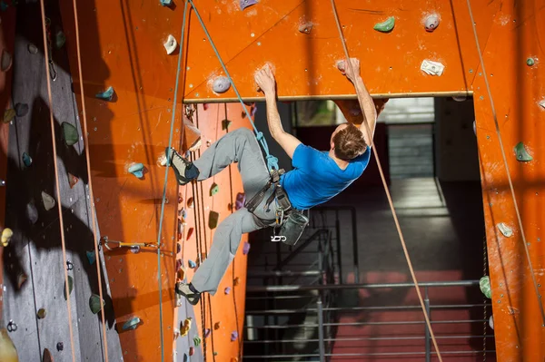 Hombre escalador practicando escalada en pared de roca en interiores —  Fotos de Stock