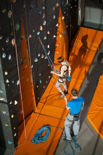 屋内ロック クライミングの壁の女性登山家が登っています。 — ストック写真