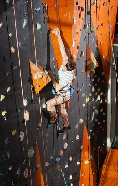 Masculino alpinista praticando escalada na parede de rocha dentro de casa — Fotografia de Stock