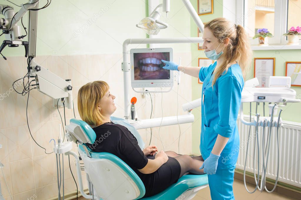 female dentist showing photograph of teeth on computer to patient