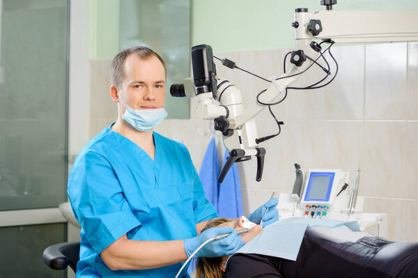 Male dentist working with microscope at modern dentist clinic