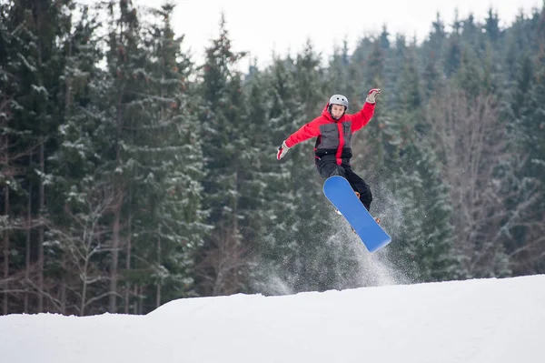 Mužské snowboardista skákání přes svah v zimě — Stock fotografie