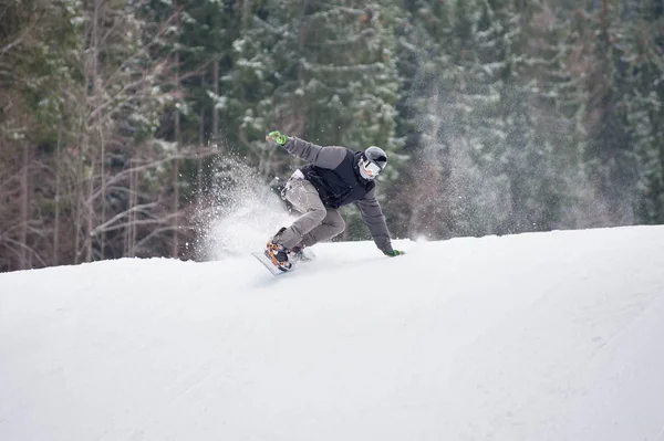 Snowboarder mâle sautant par-dessus la pente dans la journée d'hiver — Photo