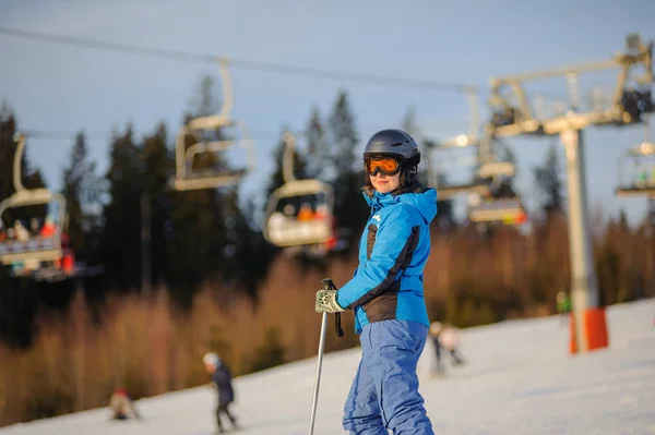 Mulher esquiadora contra ski-lift e floresta em um dia ensolarado — Fotografia de Stock