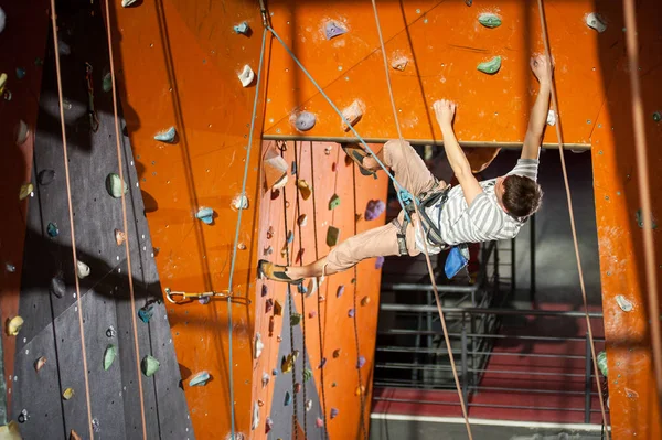 Hombre escalador practicando escalada en pared de roca en interiores —  Fotos de Stock