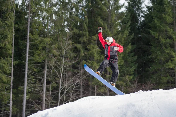 Pensionista masculino no snowboard pulando sobre a encosta — Fotografia de Stock