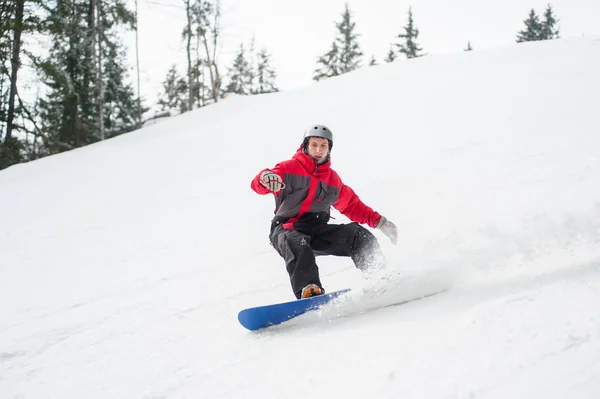 Snowboarder maschio che scende dalla montagna in giornata invernale — Foto Stock
